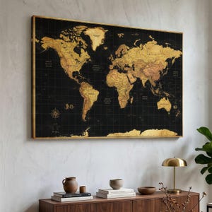 May include: A rectangular wall art piece featuring a world map with gold-colored continents set against a black background. The map includes a grid overlay, a compass rose, and clearly labeled country names in a dark, elegant font style.