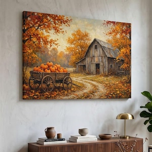 May include: A rectangular wall art print depicting a rustic wooden barn in an autumn landscape. A wooden cart filled with orange pumpkins sits on a dirt path surrounded by trees with golden and orange foliage under a soft, hazy sky.