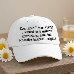 May include: A white baseball cap featuring black embroidered text that reads: Ever since I was young, I wanted to transform unstructured data into actionable business insights. The cap has a structured crown, a curved brim, and eyelet vents.