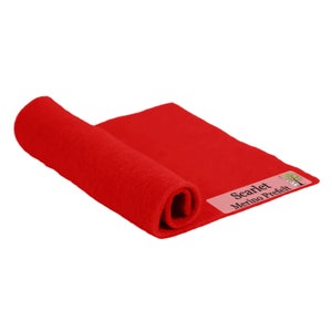 May include: A rolled-up piece of scarlet red merino prefelt fabric. The fabric is a solid, vibrant red color and has a soft, textured appearance. The label on the fabric reads "Scarlet Merino Prefelt".