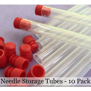 May include: A pack of 10 clear plastic needle storage tubes with red caps. The tubes are stacked on top of each other. Needle Storage Tubes - 10 Pack