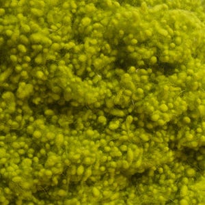 May include: Close-up of a vibrant, textured yarn in a bright, chartreuse green color. The yarn has a nubby, looped texture, creating a dense, tactile surface. This yarn is suitable for various crafting projects.