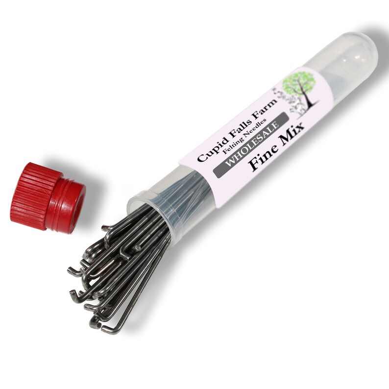 Puede incluir: Un tubo de pl&aacute;stico transparente que contiene un conjunto de agujas de fieltro finas, con una tapa roja suelta. El tubo tiene una etiqueta que dice "Cupid Falls Farm Felting Needles WHOLESALE Fine Mix" con un gr&aacute;fico de &aacute;rbol.