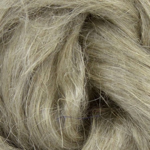 Puede incluir: Primer plano de fibra de lino cruda y natural en tonos beige y gris. Las fibras son largas, fluidas y texturizadas, creando una apariencia suave y org&aacute;nica. Esta imagen muestra la materia prima utilizada en la producci&oacute;n textil.
