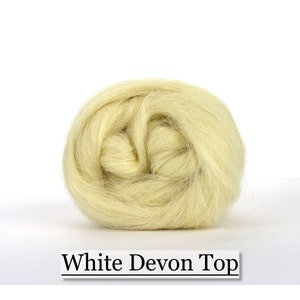 May include: A ball of pale yellow White Devon Top wool fiber, tightly wound and ready for crafting. The text "White Devon Top" is displayed in a black font at the bottom of the image. This wool is ideal for spinning, felting, and other fiber arts.