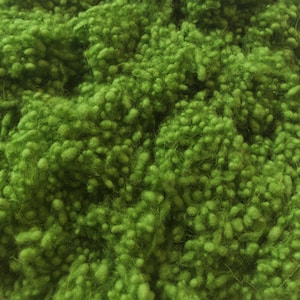 May include: Close-up of a vibrant green, textured material. The surface is covered in small, rounded, and irregular shapes, creating a dense, tactile appearance. The color is a bright, lively green, suggesting a natural or organic origin.