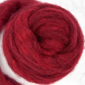 May include: A close-up of a ball of deep red wool roving. The wool fibers are tightly packed, creating a dense, textured appearance. The color is a rich, saturated red, with subtle variations in tone throughout the fibers. This wool is suitable for various fiber art projects.