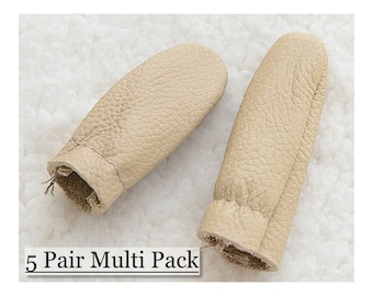 May include: Two beige leather finger protectors, designed to shield fingers. The image shows a close-up view of the finger protectors, with the text "5 Pair Multi Pack" at the bottom. The protectors are made of a textured leather material.