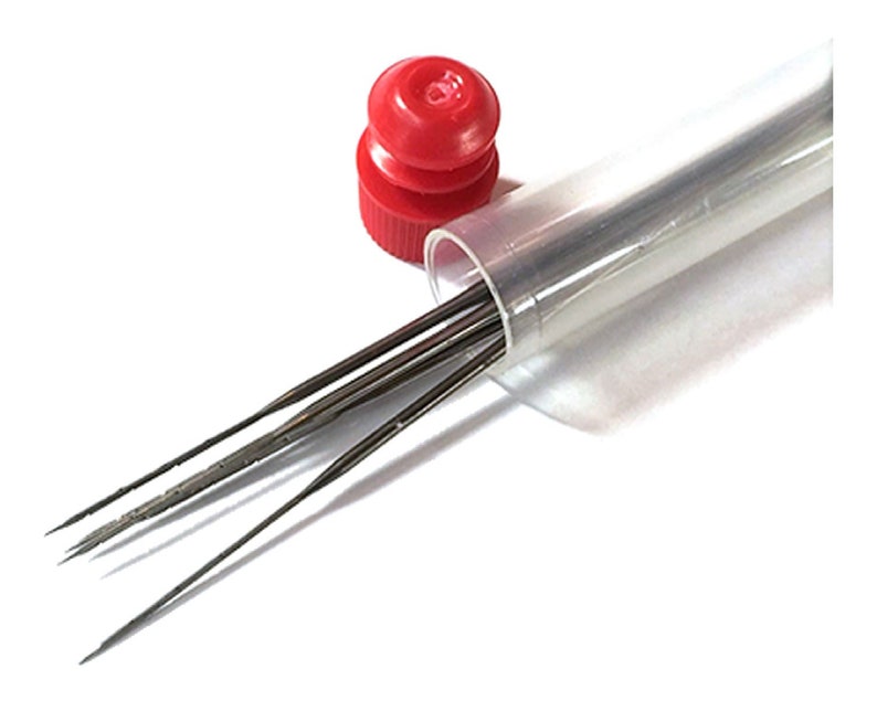 May include: A set of small, metal needle files in a clear plastic tube with a red cap. The files are thin, with pointed ends, and appear to be for detailed work. The tube is partially open, and the files are visible against a white background.