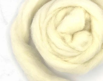 May include: Close-up of a skein of creamy white wool roving, tightly coiled in a spiral. The soft, fluffy texture of the wool is visible, with subtle variations in color. Ideal for fiber art projects.