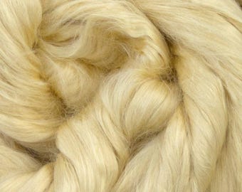 May include: Close-up of a pile of light yellow fiber, possibly wool or silk. The fibers are tightly packed and have a soft, textured appearance. The color is a warm, creamy yellow, with subtle variations in tone.