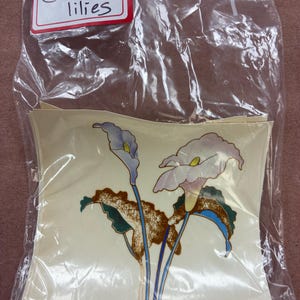 May include: A clear plastic bag containing multiple square decals featuring a floral illustration of calla lilies with white petals, yellow centers, and blue stems, with the text (4) Calla lilies printed on a white label at the top.