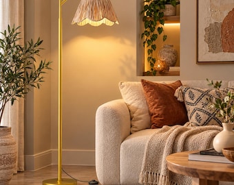 May include: A tall floor lamp with a slender gold-toned metal stand and a curved arm. The lamp features a scalloped, textured beige shade that emits a warm, soft glow, illuminating the surrounding space with a focused downward light.