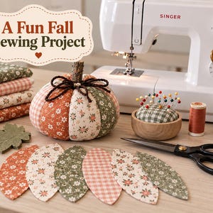 May include: A fabric pumpkin with a twig stem, surrounded by sewing supplies including a Singer sewing machine, a wooden pincushion with colorful pins, scissors, thread, and fabric scraps. Text reads: A Fun Fall Sewing Project.