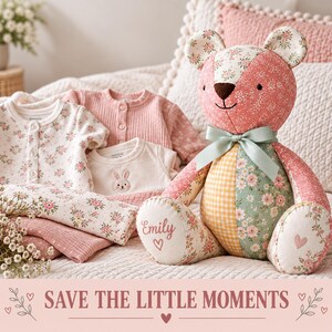 May include: A patchwork teddy bear with floral and gingham fabric panels, a sage green ribbon bow, and the name Emily embroidered on one foot. Beside it are folded baby clothes featuring floral patterns and a small embroidered rabbit design.