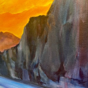 May include: A close-up of a painting depicting a rocky cliff face with a blue and purple water scene in the foreground. The sky is a vibrant orange and yellow.