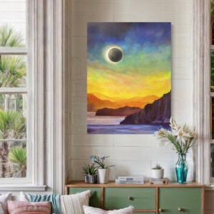 May include: A painting of a solar eclipse over a body of water with mountains in the background. The sky is a vibrant mix of blue, yellow, and green.