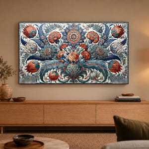 Op de afbeelding: Een rechthoekig wandkunstwerk met een dicht, symmetrisch bloemenpatroon met grote, gestileerde bloemen in tinten dieprood, oranje-bruin en donkerblauw, op een witte achtergrond met gedetailleerde, zwierige blad- en rankmotieven.