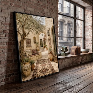 May include: A framed wall art print depicting a Mediterranean courtyard scene with a stone bench, an olive tree, patterned rugs, and terracotta pottery. The image features warm beige tones, intricate textile designs, and architectural arches.
