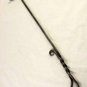 Puede incluir: Un atizador de chimenea de metal negro con un mango retorcido y un gancho en el extremo.