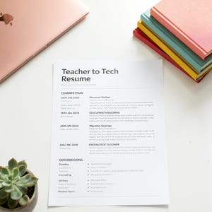 May include: A printed resume document titled Teacher to Tech Resume, placed on a white surface with a rose gold laptop, a stack of colorful notebooks, a small potted succulent, and a gold paperclip. The text Instant PDF Download is visible.