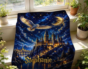 May include: A rectangular throw blanket featuring a dark blue night sky with a crescent moon, a flying owl, and a large illuminated castle on a cliff. The name Stephanie is printed in gold lettering at the bottom of the blanket.