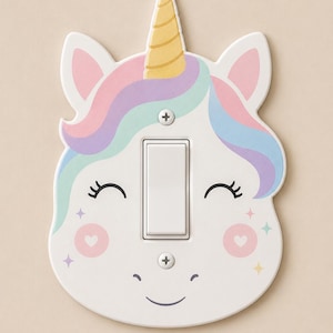 May include: A white light switch cover shaped like a unicorn head with a yellow horn, pastel pink, blue, and purple hair, closed eyes with long lashes, pink heart-shaped cheeks, and small star accents, secured with two silver-colored metal screws.