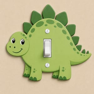May include: A light green dinosaur-shaped light switch cover featuring a central white toggle switch, two silver mounting screws, and dark green dorsal plates along the back. The dinosaur has a smiling face, spots, and four legs.