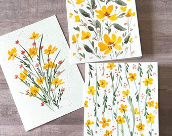 May include: Three rectangular greeting cards featuring watercolor illustrations of yellow flowers with green stems and leaves. The designs include a dense floral cluster, a vertical arrangement of stems, and a scattered pattern of small yellow blossoms.