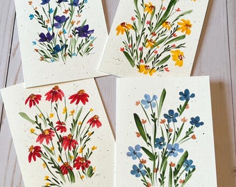 May include: Four rectangular cards featuring watercolor paintings of wildflower bouquets. One card displays purple and blue flowers, another yellow flowers, one red flowers, and the final card light blue flowers, all with green stems and leaves.