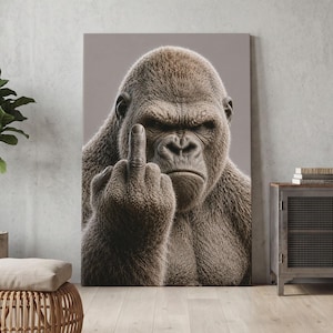 May include: A rectangular wall art print featuring a close-up portrait of a brown gorilla with a serious expression, holding up its middle finger. The gorilla has detailed fur texture and is set against a solid, neutral light gray background.