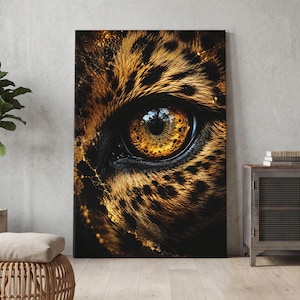Könnte beinhalten: Ein rechteckiger Wandkunstdruck mit einer Nahaufnahme eines Leopardenauges mit gold-bernsteinfarbener Iris und schwarzer Pupille. Das umgebende Fell ist mit schwarzen Flecken und goldbraunen Tönen texturiert, akzentuiert durch schimmernde goldene Farbspritzer.