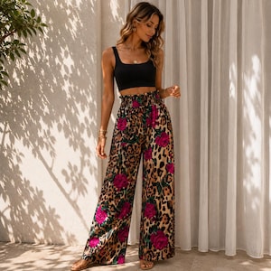 Op de afbeelding: Een zwarte mouwloze crop top gecombineerd met een broek met hoge taille en wijde pijpen, voorzien van een beige en bruin luipaardpatroon met felroze rozenmotieven. De broek heeft een geplooide elastische tailleband en een losse pasvorm.