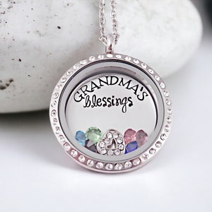 May include: Silver locket necklace with a clear glass insert and a silver chain. The locket has a silver rim with small clear crystals. The glass insert has the text "Grandma's Blessings" and colorful crystals inside.