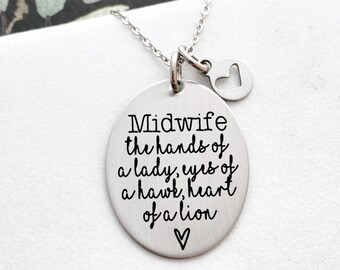 May include: A silver-toned oval pendant necklace featuring the engraved text: Midwife the hands of a lady, eyes of a hawk, heart of a lion, followed by a small heart symbol. The pendant hangs from a delicate chain with a small heart-shaped charm.