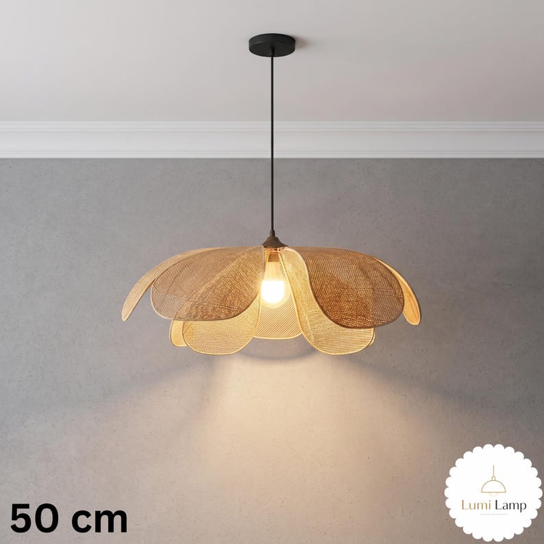 May include: A pendant light fixture with a woven tan shade shaped like a flower with overlapping petals. The lamp hangs from a thin black cord attached to a black ceiling canopy. A single light bulb is visible in the center. Text reads 50 cm.