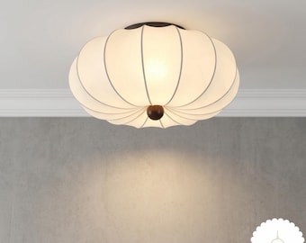 May include: A round, off-white fabric flush mount ceiling light with a pumpkin-like ribbed design and a dark brown circular center accent. The fixture emits a soft glow and features the text Lumi Lamp in the bottom right corner of the image.