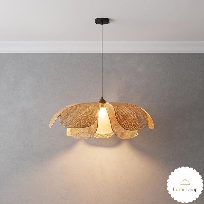 May include: A pendant lamp featuring a woven tan shade shaped like a flower with multiple overlapping petals. The light hangs from a thin black cord attached to a circular black ceiling canopy. The text Lumi Lamp is visible in the corner.