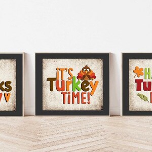 May include: Three Thanksgiving-themed printable signs with a rustic background. The first sign says "Give Thanks" with a row of colorful hearts at the bottom. The second sign says "It's Turkey Time!" with a cartoon turkey. The third sign says "Happy Turkey Day!" with a leaf and a heart.