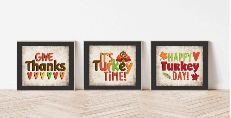 May include: Three Thanksgiving-themed printable signs with a rustic background. The first sign says "Give Thanks" with a row of colorful hearts at the bottom. The second sign says "It's Turkey Time!" with a cartoon turkey. The third sign says "Happy Turkey Day!" with a leaf and a heart.