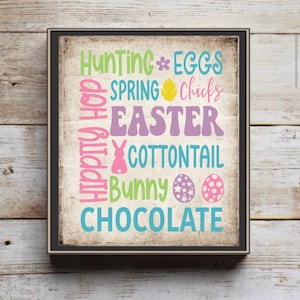 May include: Framed Easter-themed wall art with a distressed background. The artwork features colorful text including "Hunting", "Eggs", "Spring", "Easter", "Bunny", and "Chocolate". Decorative elements include a flower, chick, bunny, and Easter eggs.