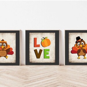 May include: Three framed prints with a Thanksgiving theme. The center print features the word "LOVE" with a pumpkin in the "O". The prints on either side feature cartoon turkeys with different hats and expressions.