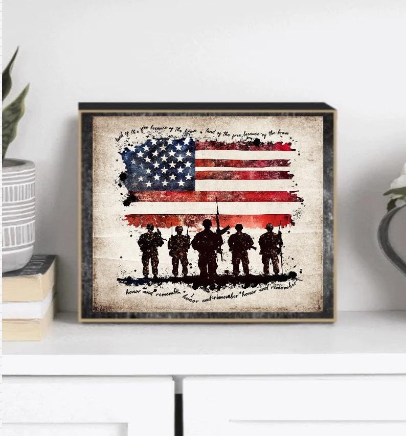 May include: A framed print with a vintage aesthetic featuring a silhouette of soldiers standing in front of an American flag. The text reads "Land of the free because of the brave. Honor and remember."