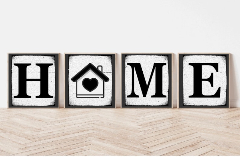 Op de afbeelding: Vier zwarte en witte houten borden die het woord "HOME" spellen met een huissymbool met een hart in het midden van het tweede bord.