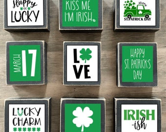 Puede incluir: Nueve bloques de madera con temática del Día de San Patricio. Los bloques presentan texto e imágenes en verde, negro y blanco. El texto incluye "Happy Lucky", "Kiss Me I'm Irish", "St. Patrick Day", "March 17", "Love", "Happy St. Patrick's Day", "Lucky Charm" y "Irish-ish".