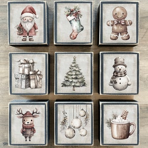 May include: Nine wooden blocks with various Christmas-themed illustrations. The blocks feature a Santa Claus, a stocking, a gingerbread man, a snowman, a Christmas tree, a reindeer, ornaments, and a mug of hot chocolate.