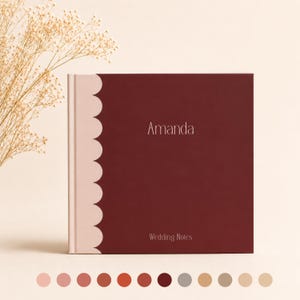 Puede incluir: Un libro cuadrado con una cubierta de color burdeos intenso que presenta el nombre Amanda y el texto Wedding Notes en letras blancas. El lomo tiene un diseño festoneado de color rosa claro. Hay una fila de doce círculos de colores en la base.