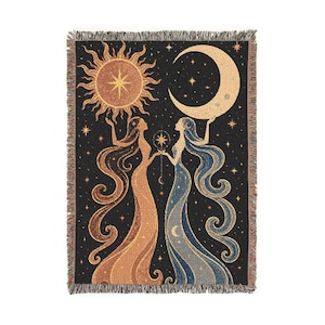 Peut inclure: Un plaid tissé rectangulaire sur fond noir avec un motif céleste. Deux silhouettes aux longs cheveux fluides se font face, l'une tenant un soleil doré et l'autre un croissant de lune, le tout entouré d'étoiles sur le tissu.