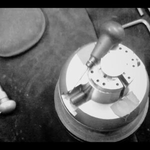 May include: A black and white image of a metal jewelry making tool with a small metal rod attached to a handle. The tool is used to hold jewelry pieces in place while they are being worked on.