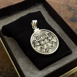 May include: A silver pendant featuring a detailed engraved design of two owls facing each other. The pendant is round and has a bail for attaching a chain.